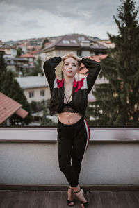 Portrait of young woman with hands in hair standing on building terrace