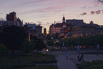 Trees and buildings against sky at sunset
