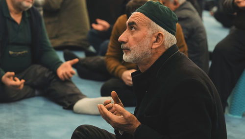 Old muslim man with a prayer cap praying to allah at mosque in ramadan month