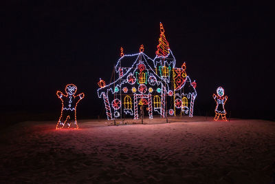 Illuminated christmas lights at amusement park ride at night