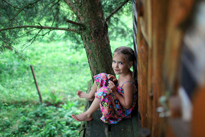 Full length of girl on tree trunk in forest