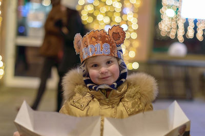 Portrait of boy smiling while standing in city at night