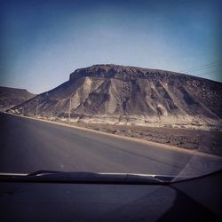 Road by mountain seen through car windshield