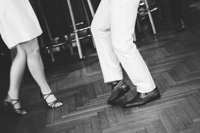 Low section of man and woman standing on hardwood floor