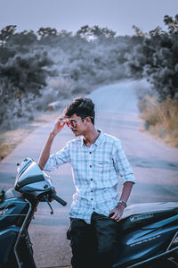 Young man with umbrella standing on road