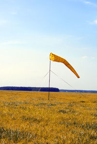 Yellow flag on field against sky
