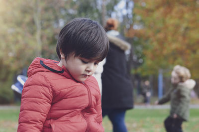 Close-up of boy wearing padded jacket sitting at park