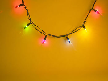 Colorful illuminated string lights hanging on wall at night