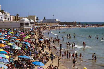 Group of people on beach against clear sky