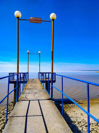 Pier over sea against clear blue sky