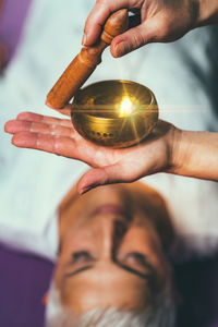 Cropped hands of woman playing singing bowl for customer in spa