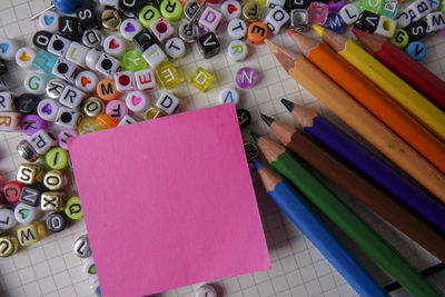 Directly above shot of alphabet beads with school supplies and easel on paper