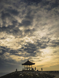 Silhouette lifeguard hut on beach against sky during sunset