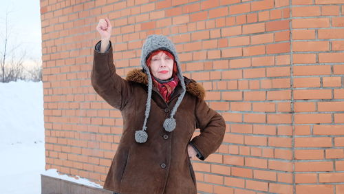 Full length of woman standing against brick wall