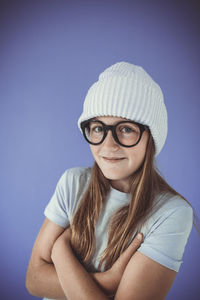 Portrait of young woman wearing hat against blue background