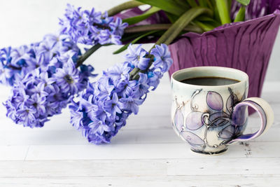 Purple hyacinth flowering plant with a cup of coffee in front.