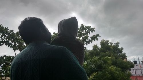 Rear view of people looking at tree against sky