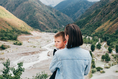 Woman carrying son while standing on mountain