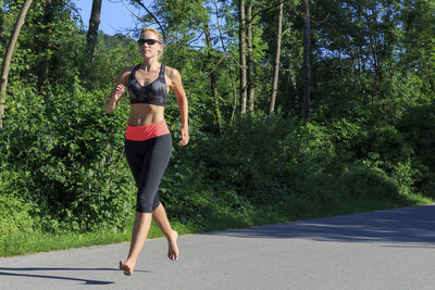 Full length of young woman on road against trees
