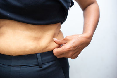 Midsection of woman standing against white background