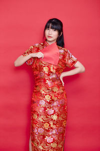 Portrait of woman standing against red background