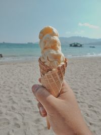 Close-up of hand holding ice cream cone at beach