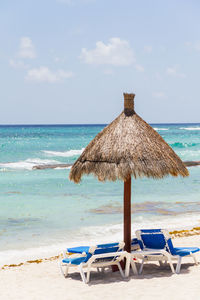 Chair on beach by sea against sky