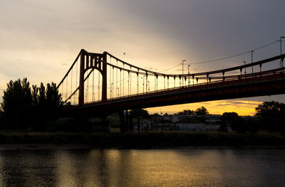 Bridge over river against sky during sunset