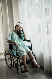 Woman with bandaged head and leg sitting on wheelchair hospital