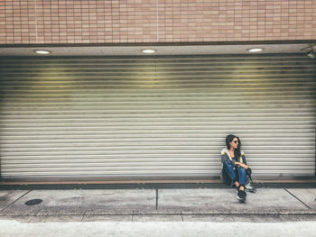 Full length of woman sitting against wall