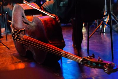 Low section of musician sitting by double bass on stage