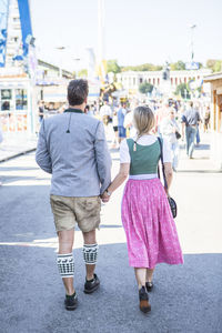 Man holding hands of woman while walking on street at event