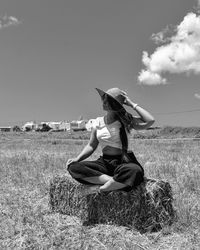 Woman sitting on field against sky