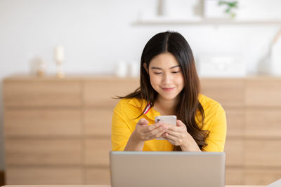 Smiling young woman using mobile phone