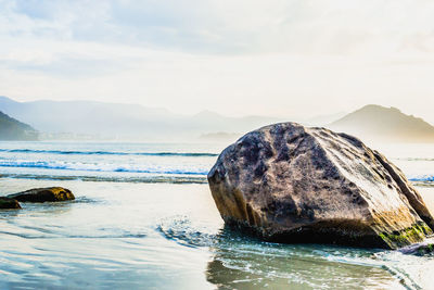 Scenic view of rocks by sea against sky