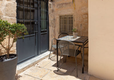 Empty chairs and tables against building