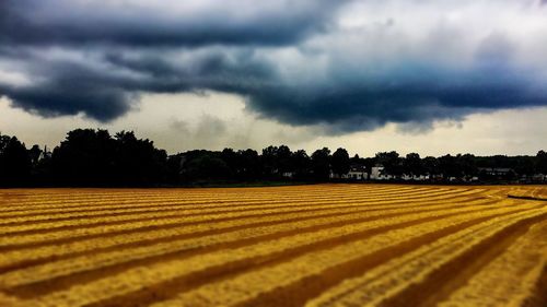 Scenic view of field against storm clouds