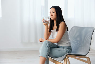 Portrait of young woman sitting on sofa at home