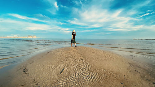 Rear view of man standing on beach against sky