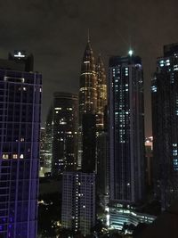 Illuminated buildings in city against sky at night