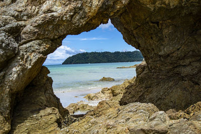 Rock formation on sea shore against sky