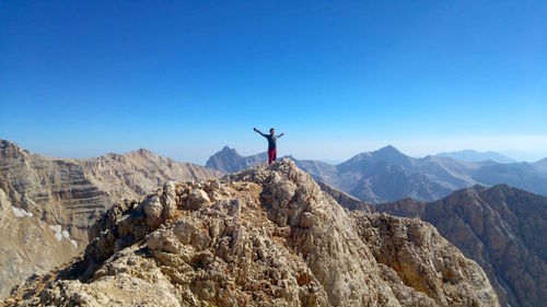 Rear view of person standing on rock against sky