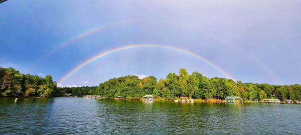 Scenic view of rainbow over river against sky