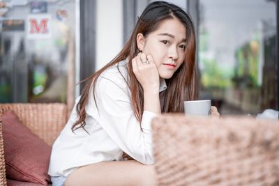 Young woman drinking coffee while sitting outdoors