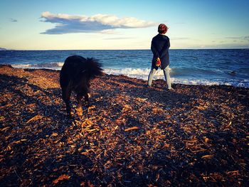 Full length of man standing on beach against sky during sunset