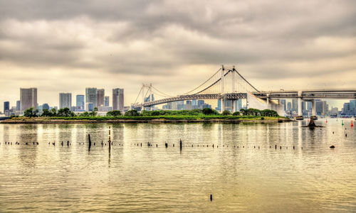 Bridge over river in city against sky