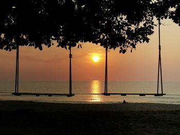 Silhouette trees on beach against sky during sunset