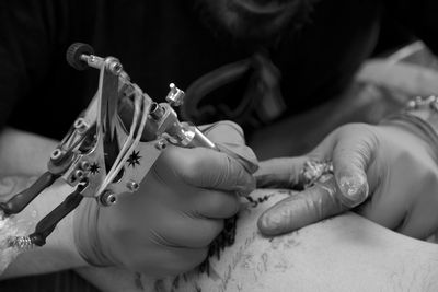 Cropped hands of man tattooing