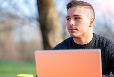 Young man using laptop at park