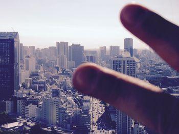 Close-up of hand holding cityscape against sky